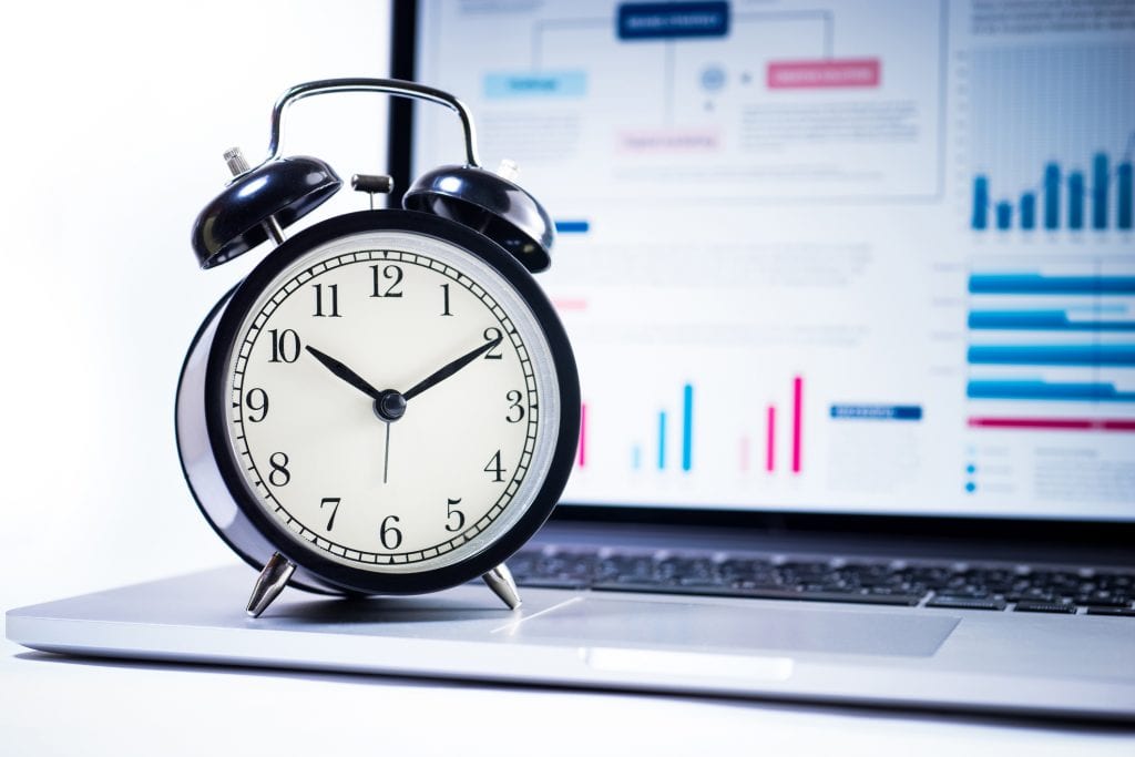 alarm clock with stock graph chart in laptop screen background